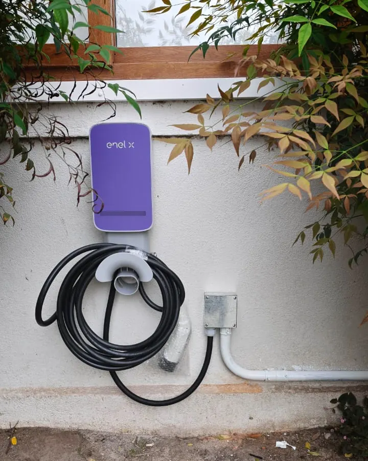 Cargador Enel X instalado bajo una ventana, con su canalización hasta una caja metálica