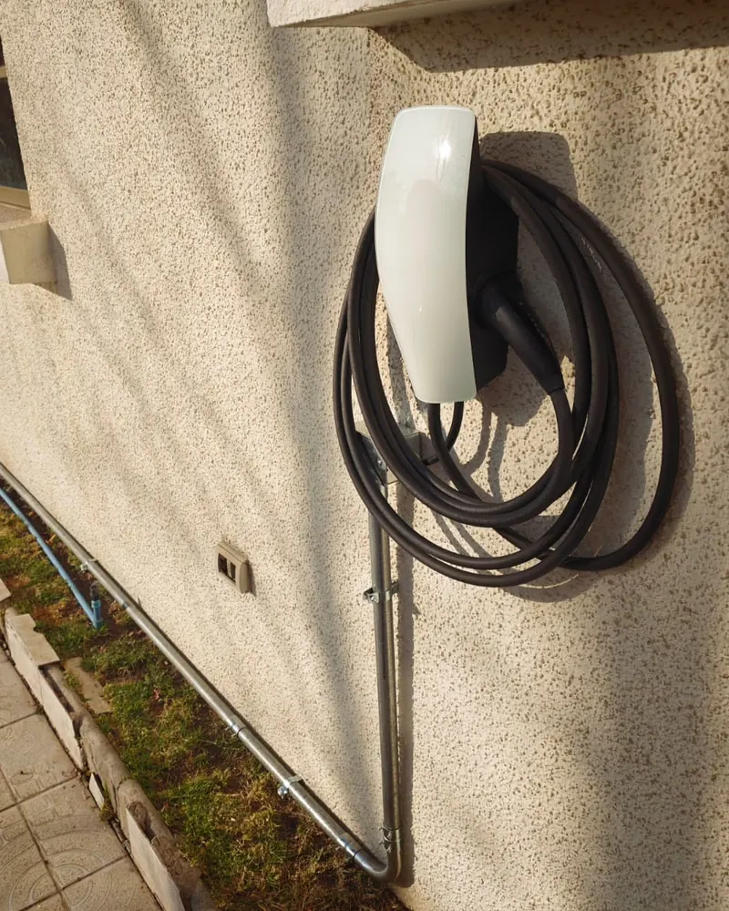 Wall Connector de Tesla en el muro exterior de una casa, con el tubo EMT bajando desde el recorrido